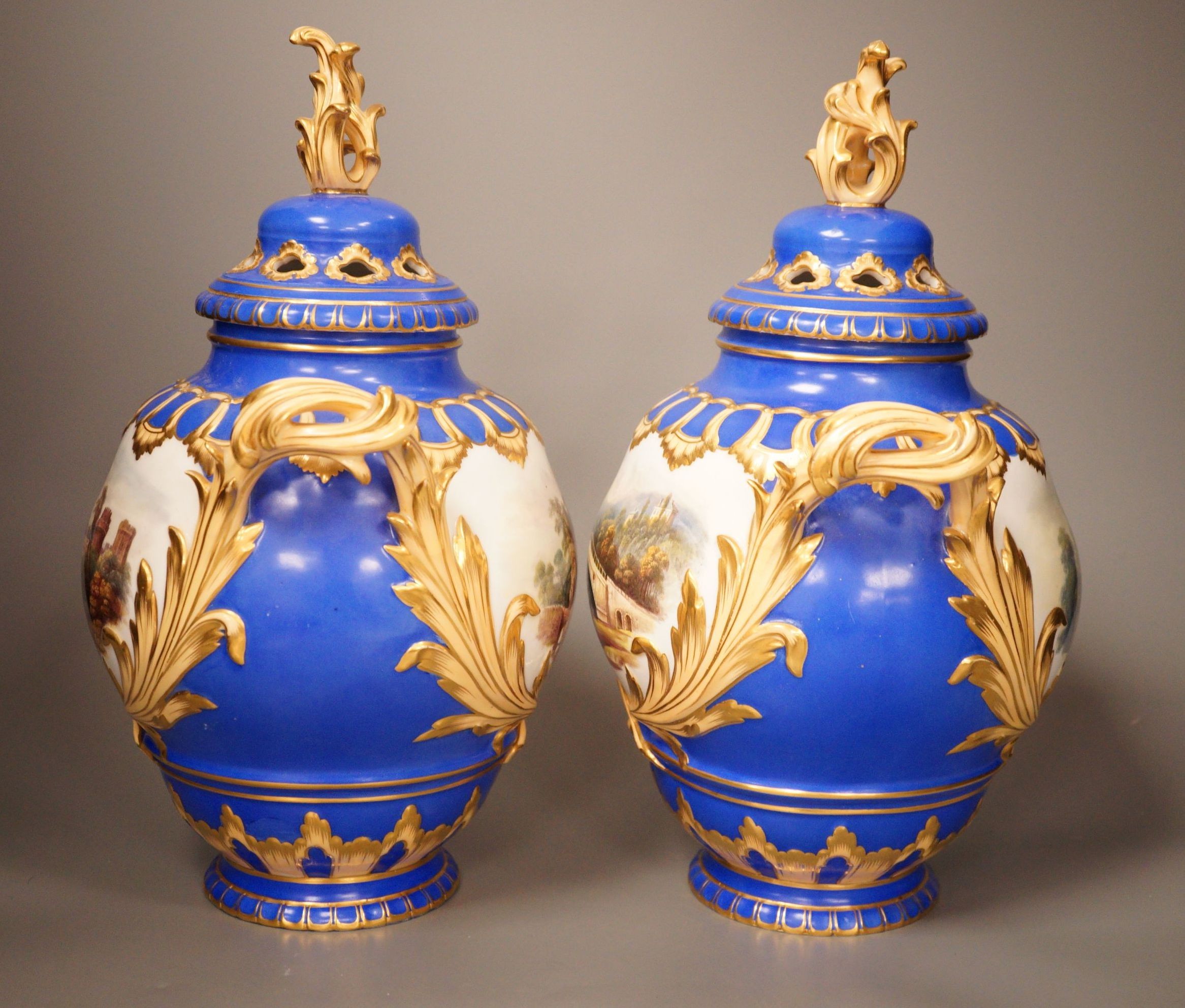 A pair of English bone China lidded two-handled vases, painted with river landscapes, within blue and gilt fields, circa 1840, 33cm